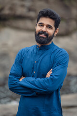 handsome indian bearded black hair man wearing traditional clothes blue kurta. hands folded and...