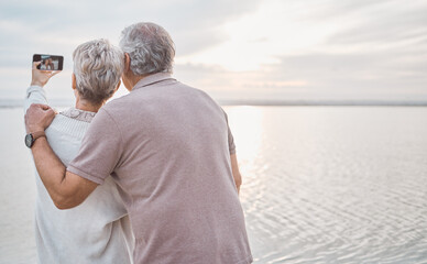 Fototapeta premium Selfie, back and senior couple by beach to relax on holiday, vacation and romance together. Marriage, travel and man and woman embrace for affection, bonding and space to take picture for memory