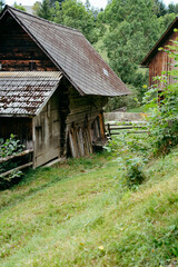 Traditional wooden barns on a hillside in a serene rural landscape surrounded by lush greenery on a sunny day