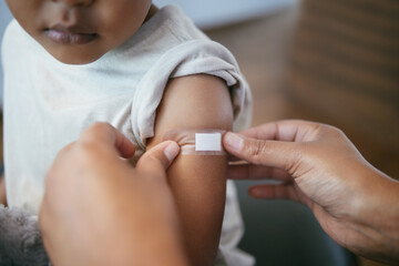 Hands, pediatrician and arm of kid with plaster for immunization shot, medication or injection. Healthcare, consultation and doctor with child for medical vaccine treatment with bandage in clinic.