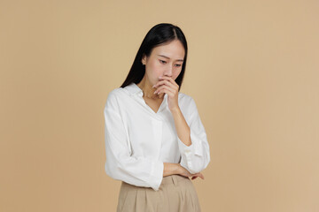 Thoughtful Woman with Hand on Mouth in Pensive Pose, Beige Background