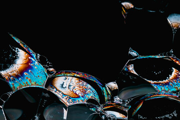 Close-up of soap foam bubbles with iridescent surface areas on a black background