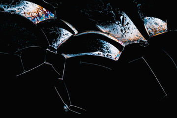 Close-up of soap foam bubbles with iridescent surface areas on a black background