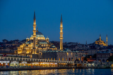 Türkiye. Istanbul. The new mosque or Valide Sultan Camii with the Galata bridge and ın the background the suleymaniye mosque at dusk