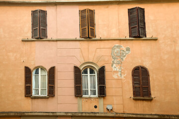 Facade of a building with peeling wall and windows with wooden shutters