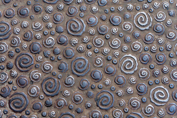 Textured outdoor flooring sidewalk design with metal elements in the form of spirals.