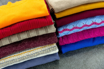 Stack of folded warm clothes close-up. Sweaters and cardigans for autumn and winter. Knitwear.