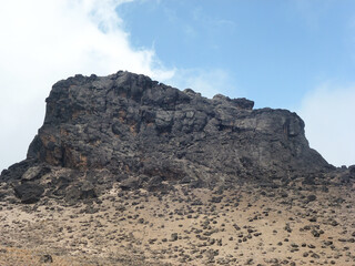 The rocky peak of a small rocky mountain against the background of the blue sky. Tourist route and nature