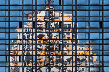 Curved reflection of a weird house on the glass facade of the building