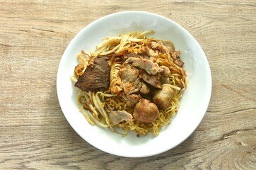 dry boiled Chinese yellow egg noodles with braised beef and meatball dressing black sweet soy sauce topping mashed peanut on plate