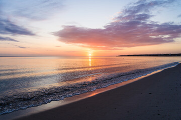Orange sunrise with colorful clouds at the baltic sea in a bay near Glowe