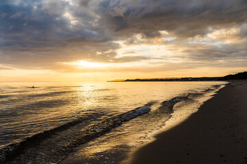 Small waves at a bay of the baltic sea near Glowe in yellow sunrise with colorful clouds