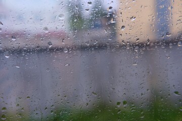 Raindrops on the window of a train carriage in cloudy rainy weather.
