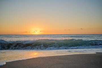 Waves crashing into beach at sunrise or sunset