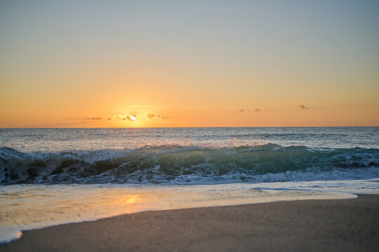 Waves crashing into beach at sunrise or sunset