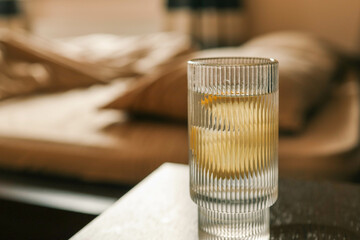 A glass of lemon water resting on a soft, beige bed sheet, evoking a serene and relaxed morning atmosphere
