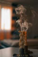 A close-up of an extinguished candle with smoke rising from the wick, surrounded by melted wax