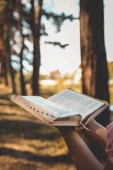 Christian illustration of a girl holding an open Bible against a forest backdrop
