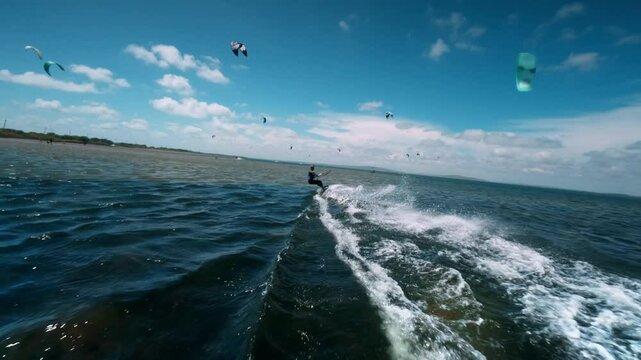 Surfer with turquoise paraglider wing speeds through blue lagoon. Best places for kiteboarding
