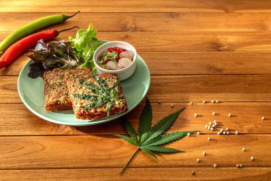 Dish of hot delicious cannabis fried minced pork toat menu with sweet and sour sauce on wooden table background. Copy space text. Eatable decor recipe local international food herb for concept