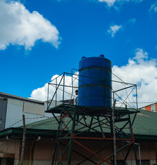 Obraz premium A boy climbing up to repair a blue tank under the blue sky
