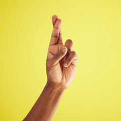 Hope, fingers crossed and model hand in studio wishing for success, winning or achievement. Praying, optimism and person with luck gesture, emoji and future isolated on yellow background space