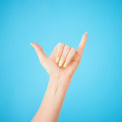 Hand, gesture and shaka with model in studio on blue background feeling carefree closeup. Emoji, sign and signal with person greeting, cheer or winning surfing for good news or victory symbol