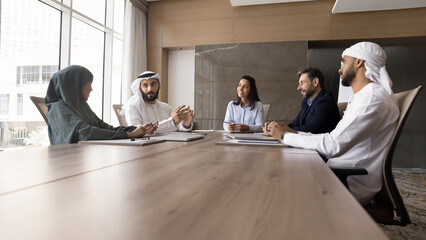 Multiethnic company colleagues meeting at large table for negotiation, teamwork, discussing project...