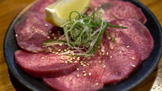 Slice of beef ox tongue gyutan lemon Japanese yakiniku bbq food