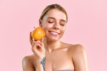 A beautiful girl with healthy glowing skin poses with a yellow apple. The concept of a healthy lifestyle, vitamins and the importance of nutrition for good skin. A cosmetic ingredient or product.