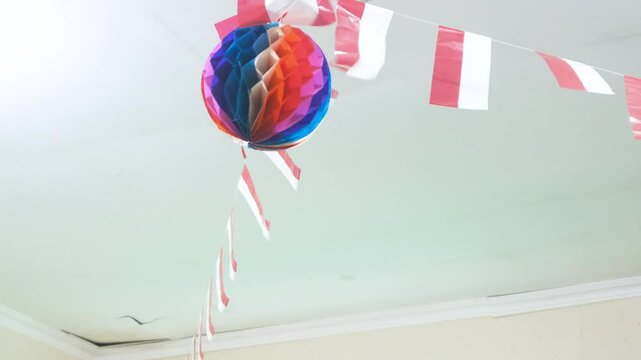 Indonesian plastic flags lined up on a white string, set against a white background with paper lanterns. This scene captures a festive and patriotic atmosphere, ideal for projects related to national.