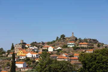 historic village of Sortelha, Portugal, featuring stone houses and ancient fortress walls under a bright blue sky. This charming medieval village is a perfect example of Portuguese cultural heritage.
