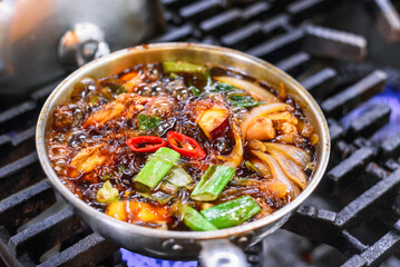 Cooking Andong Jjimdak: Ingredients in a Pot with Focus on Sliced Red Chili Pepper on the Stove