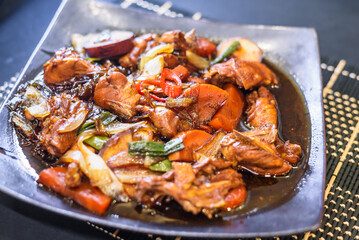 Served Andong Jjimdak: Finished Dish on Square Plate with Focus on Sliced Red Chili Pepper and Table Setting