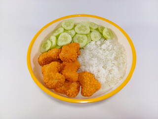 Crispy chicken nuggets, rice, and cucumber slices served on a plate with yellow accents against a white background, highlighting a simple yet appetizing meal