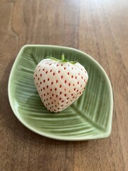 緑の皿に乗せた白いイチゴ