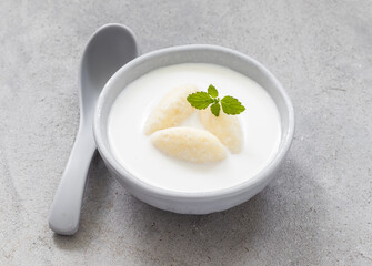 Milk soup with sweet cottage cheese quenelles. With fresh mint. On a plate. 