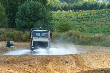 Fototapeta premium A truck pours water on a sandy road to remove dust. Preparation of a dirt track for auto racing. Road works.