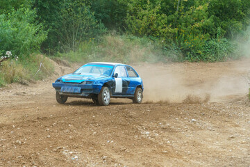 A close-up of an autocross racing car. Clouds of dust and sand burst out from under the wheels. Off-road racing.