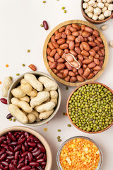 Assortment of legumes in bowls on a light background, top view. Mung beans, chickpeas, peanuts, beans, lentils.