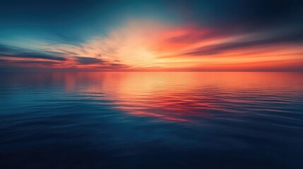 Obraz premium A calm sea at dusk, with the sky transitioning from blue to deep orange and the water reflecting the colors.