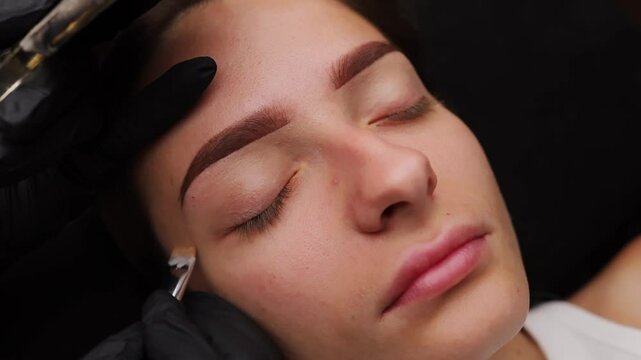 Performing light makeup after the permanent makeup procedure. Light permanent eyebrow makeup, performing eyebrow tattooing