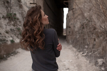 A beautiful woman dressed in gray pants and a sweater walks against the background of a career in stylish clothes