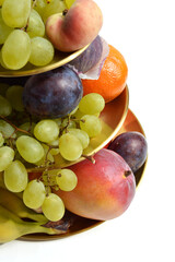 Appetizing, decadent gold tiered fruit platter isolated on white background, luxury, gourmet food presentation, apple, banana, grapes, mandarine orange, fig, mango, plum, peach detailed, close up.