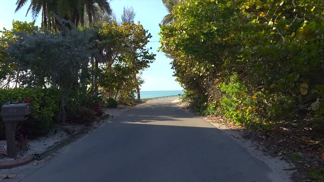 Car point of view driving on scenic road in sunny Florida. Casey Key coastal residential community picturesque streets.
