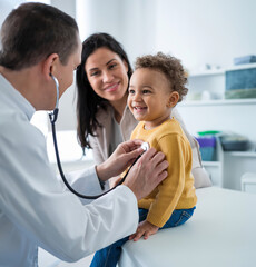 Pediatrician Examining Happy Toddler with Stethoscope in a Medical Clinic, Mother Smiling in Background
