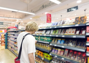 Young man shopping in supermarket, reading product information