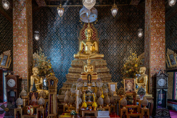 Thailand, August 11, 2024, Wat Phitchaya Yatikaram Worawihan, Golden Buddha statue surrounded by ornate decorations in a serene temple interior at dusk
