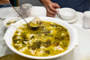 Simple and authentic Sichuan cuisine of preserved vegetable and seaweed soup with slices of fish meat, being served
