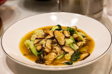 Serving of simple and authentic Sichuan cuisine of braised sliced mushroom with bok choy or chinese cabbage.